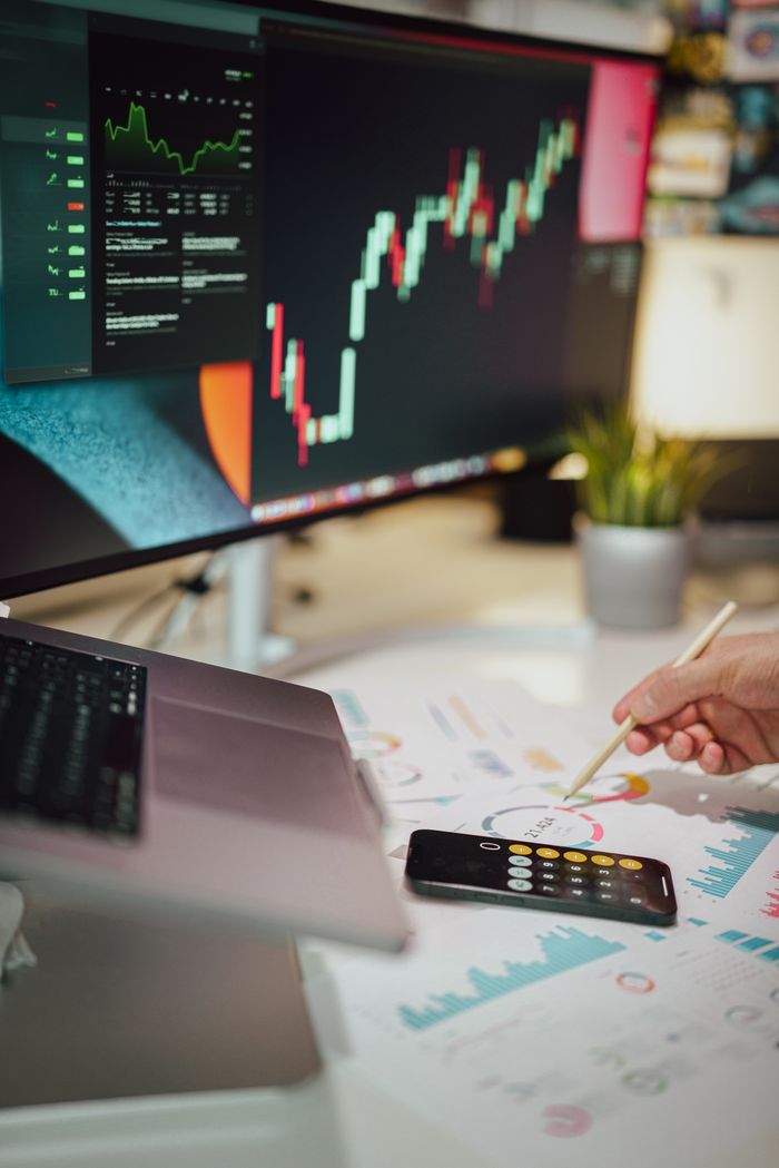 about-us Insightful business analytics with graphs on monitor, papers, and phone calculator.
